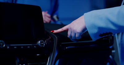 Finger prüft den Touchscreen eines Fahrzeugarmaturenbretts im Qualitätstest