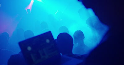 Nachtclub mit DJ und tanzender Menge in blauem Licht und Nebel