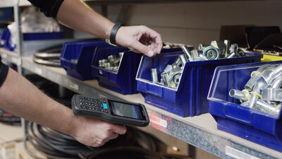 Lagerarbeiter scannt den Barcode an Kleinteilboxen mit einem Handscanner