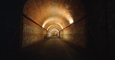 Tunnel aus Backstein: Fahrt vom dunklen Eingang ins warme Licht Tunnel aus Backstein: Fahrt vom dunklen Eingang ins warme Licht, Backsteintunnel, beleuchteter Tunnel und Tunneleingang als