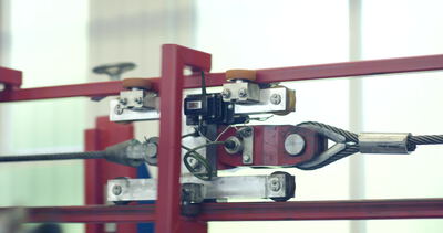 Stahlseil läuft durch eine Spannvorrichtung an einem Prüfstand in der Werkshalle: Stahlseil Prüfstand, Spannvorrichtung Fabrik