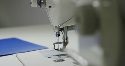Nähmaschinennadel näht blauen Stoff in der Schneiderei Nähmaschinennadel näht blauen Stoff in der Schneiderei, Nähmaschine Nadel Nahaufnahme, Nähnadel blauer Stoff und Nähfuß