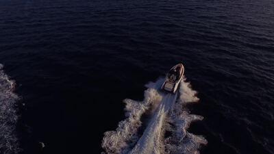 Drohnenaufnahme eines Motorboots auf offener See im Sonnenuntergang