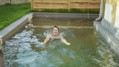 Frau schwimmt im Naturbadeteich an der frischen Luft