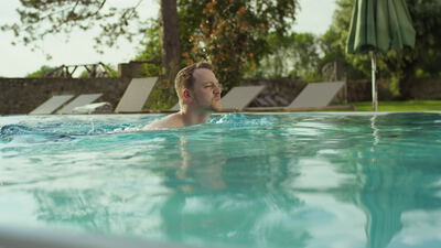 Mann schwimmt entspannt im Außenpool eines Wellnesshotels