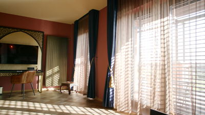 Sonnendurchflutetes Hotelzimmer mit Vorhängen und Ledersessel