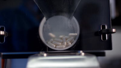 Kapselfüllmaschine dosiert weiße Kapseln in der Pharmaproduktion Kapselfüllmaschine dosiert weiße Kapseln in der Pharmaproduktion, Kapselfüllmaschine Video lizenzfrei, Pharmaproduktion