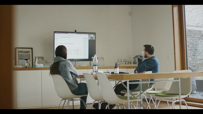 Zwei Kollegen arbeiten gemeinsam am großen Monitor im Büro