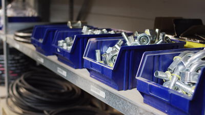 Blaue Lagerboxen mit Metallfittingen stehen im Regal einer Werkstatt