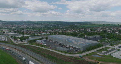 Luftaufnahme eines Logistikzentrums mit Solardach an einer Autobahn