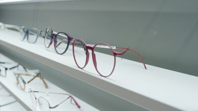 Brillengestelle liegen aufgereiht im Regal eines Optikergeschäfts