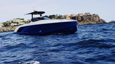 Luxusmotoryacht fährt vor einer Küste mit Villen im Sonnenschein