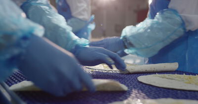 Mitarbeiter rollen Wraps mit Käse in der Lebensmittelproduktion