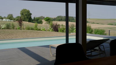 Blick durch eine große Glasfassade auf Pool und Terrasse eines modernen Hauses