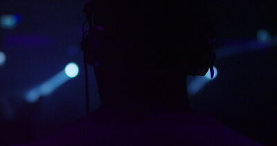 Silhouette einer Person vor blauen Scheinwerfern in dunkler Veranstaltungshalle