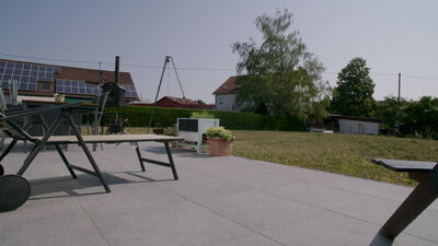 Moderne Terrasse eines Wohnhauses mit Gartenmöbeln und Kugelgrill