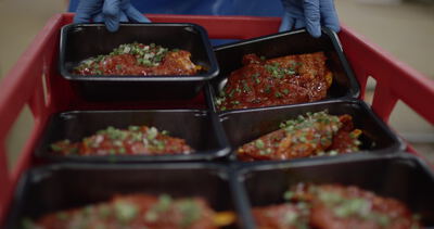 Schalen mit mariniertem Fleisch werden in rote Kisten gestapelt
