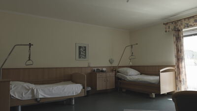 Pflegezimmer mit zwei Betten und Haltegriffen am Fenster