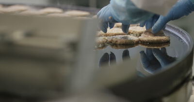 Frikadellen werden von Hand auf die heiße Bratfläche gelegt