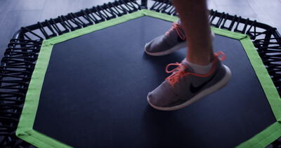 Nahaufnahme eines Sneakers beim Sprung auf grün eingefasstem Trampolin