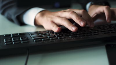 Hände tippen auf einer Tastatur im dunklen Büro