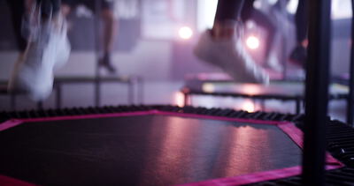 Nahaufnahme weißer Sneaker beim Springen auf pink umrandetem Trampolin
