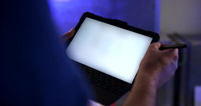 Techniker bedient ein Tablet mit Eingabestift in blauer Industrieumgebung