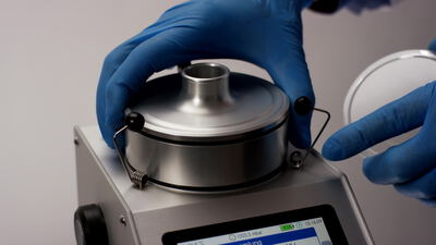 Hände in blauen Handschuhen bedienen ein Laborgerät mit Touchscreen