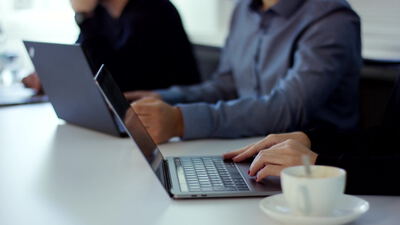 Person tippt am Laptop im hellen Büro neben einer Kaffeetasse, Büroarbeit, Person am Laptop und Business als 4K Stockvideo