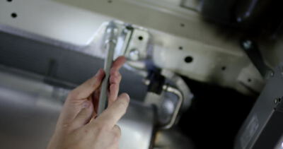 Hand steckt einen Metallstift in eine Lochplatte