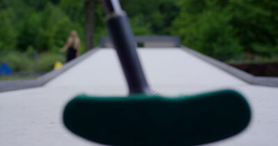 Minigolfschläger vor dem Loch auf einer Minigolfbahn im Grünen an einem Sommertag