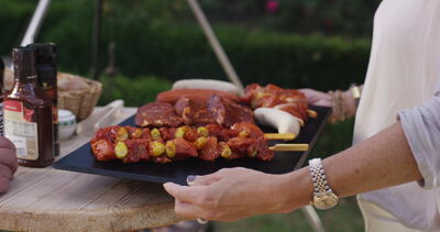 Marinierte Fleischspieße Steaks und Würste werden auf einer Platte zum Grill im Garten getragen