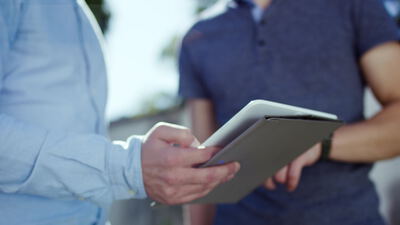 Zwei Männer besprechen Daten auf einem Tablet im Freien
