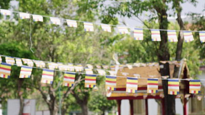 Bunte buddhistische Gebetsfahnen zwischen Bäumen im Tempelpark
