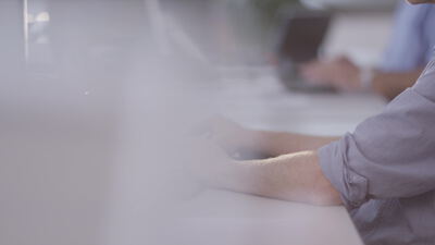 Hand an Computermaus und Tastatur an einem Büroarbeitsplatz