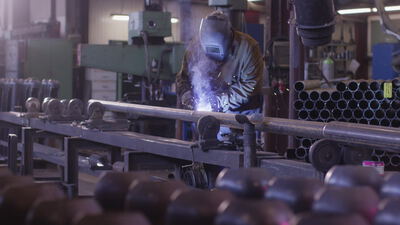 Schweißer verbindet Stahlrohr in der Metallwerkstatt