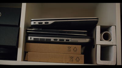 Gestapelte Laptops auf einem Büroregal über flachen Kartons
