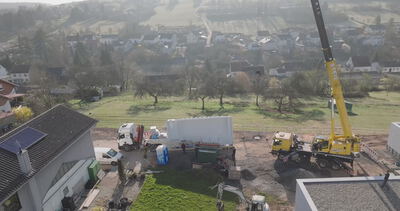 Luftaufnahme einer Baustelle mit gelbem Mobilkran in einem Wohngebiet