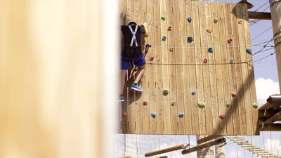 Mann klettert an der Holzwand mit bunten Klettergriffen, Kletterwand Aufnahmen, Kletterwand Video lizenzfrei und