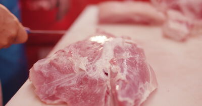 Zuschnitt von rohem Schweinefleisch auf dem Schneidbrett in der Fleischerei