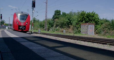 Roter Regionalzug am Bahnsteig bei Sonnenschein