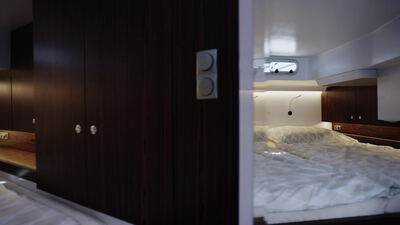 Gemütliche Yachtkabine mit dunklem Holzschrank neben dem Bett