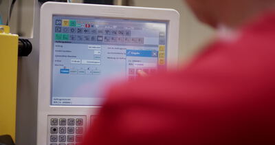 Hand bedient den Touchscreen einer Spritzgussmaschine