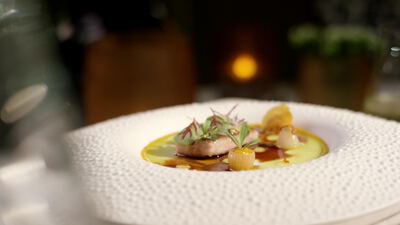 Glasiertes Fleisch mit Püree und Kräutern im tiefen Teller