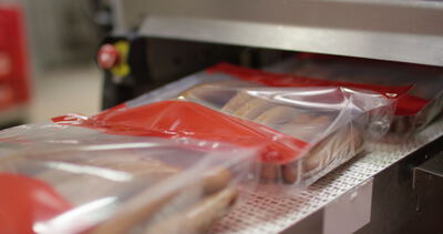 Vakuumverpackte Würstchen laufen durch die Verpackungsmaschine