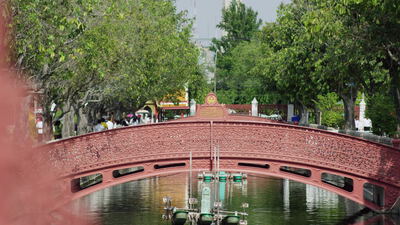 Verzierte rote Bogenbrücke über einen Kanal in Thailand