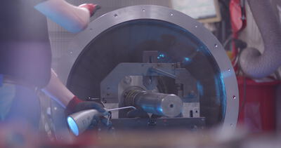 Arbeiter erwärmt ein Metallbauteil mit dem Gasbrenner an der Verseilmaschine