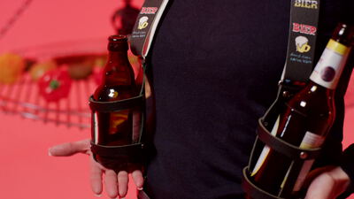Person hält eine Bierflasche in einem umgehängten Flaschenhalter