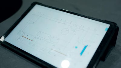 Tablet zeigt ein technisches Anlagenschema auf einem dunklen Tisch