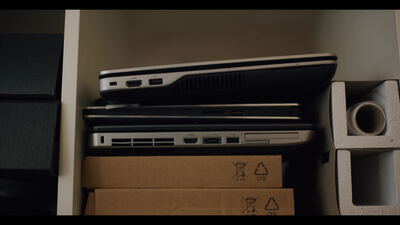 Aufeinandergestapelte Notebooks auf einem Büroregal mit Kartons